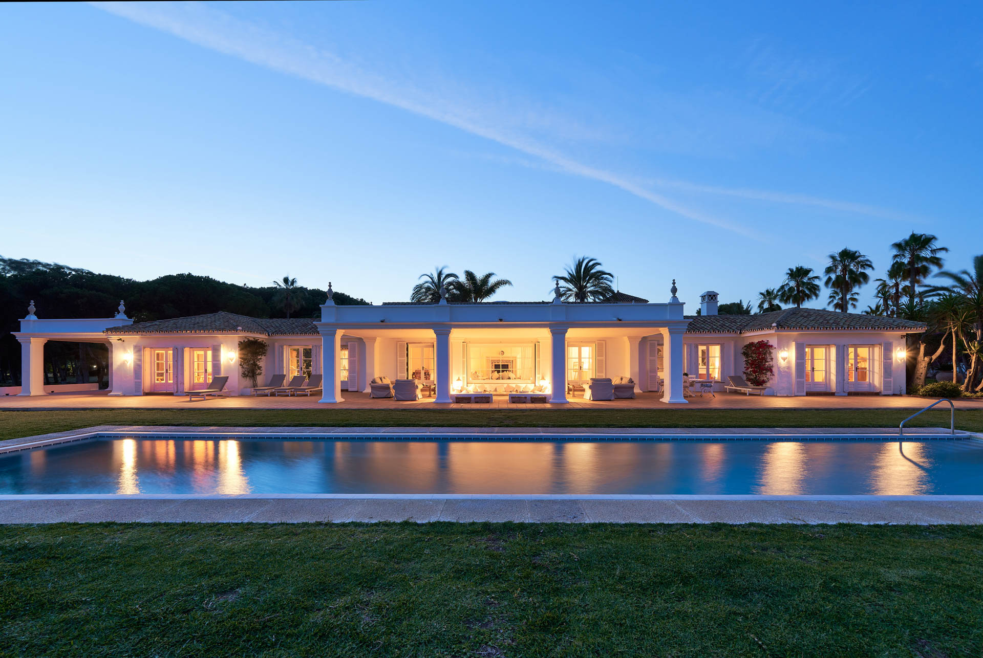 Imagen de noche en una piscina y vista frontal de una casa.